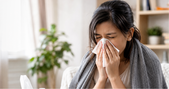 Woman suffering from allergic rhinitis with sneezing and nasal congestion at home